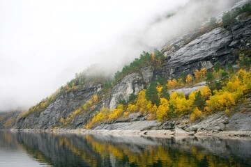 Misty autumnal mountainside reflected in calm water