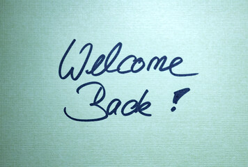 Welcome Back! Green note with handwritten text. Teamwork, welcoming ceremony, greeting, message.