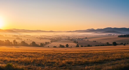 Obraz premium Golden Sunrise Over Rolling Hills and Foggy Valley
