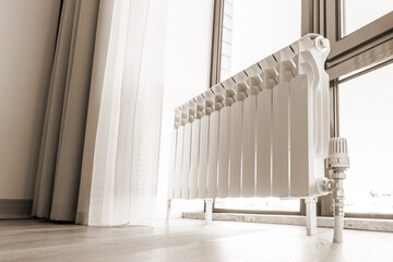 White big radiator near window in modern room, sepia toning