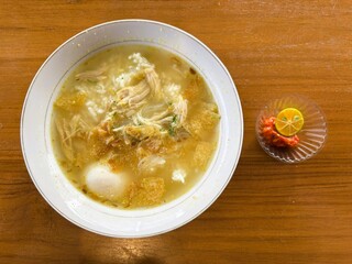Fresh soup menu with pieces of egg and shredded chicken plus chili sauce and orange slices.