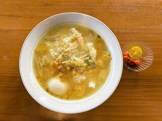 Fresh soup menu with pieces of egg and shredded chicken plus chili sauce and orange slices.
