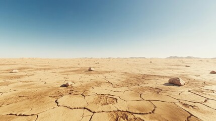 Arid desert landscape with cracked earth and distant mountains under a clear blue sky on a hot sunny day