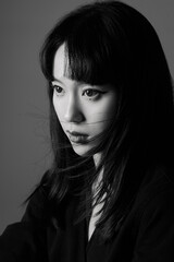 Woman in black shirt with long hair and intense gaze in a close-up portrait.