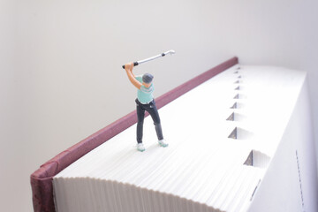 Miniature Figure Vacuuming a Large Book in Surreal Conceptual Scene