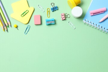 School supplies including notebook, pencils and stationery on green background