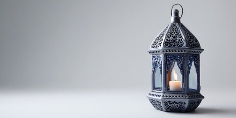 Ornate silver lantern with blue glass panels and a lit candle stands on a plain gray background.