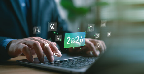 Businessman typing on laptop with futuristic interface showing target year 2026 and business icons. Concept of new year goals, business resolutions and strategic planning for future success.