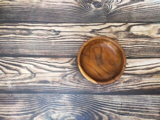 Wooden saucer or small wooden plate on a wooden table.