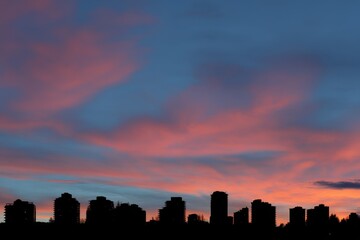 Colorful Sunset Over City Skyline with Beautiful Clouds and Silhouette