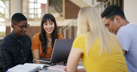 Laptop, conversation and people in library with studying for college exam, test or assignment together. Computer, happy and students with education for assessment with teamwork at university campus.