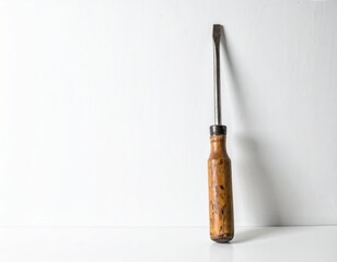 Screwdriver with a wooden handle leaning against a white background