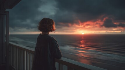 Fototapeta premium A person contemplating the sunset over the ocean, reflecting on life's beauty and tranquility from a balcony.