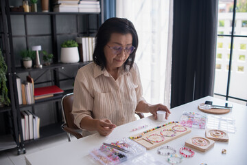Fototapeta premium Mature asian woman&nbsp;making handmade jewellery accessories handcraft hobby