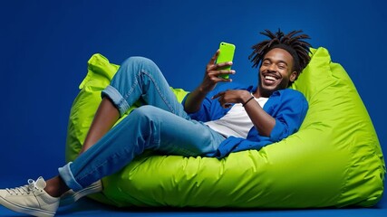 A man sitting on a bean bag chair holding a cell phone - Powered by Adobe