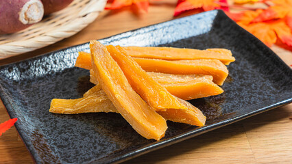 黒皿に盛られた干し芋と秋の紅葉とさつまいも