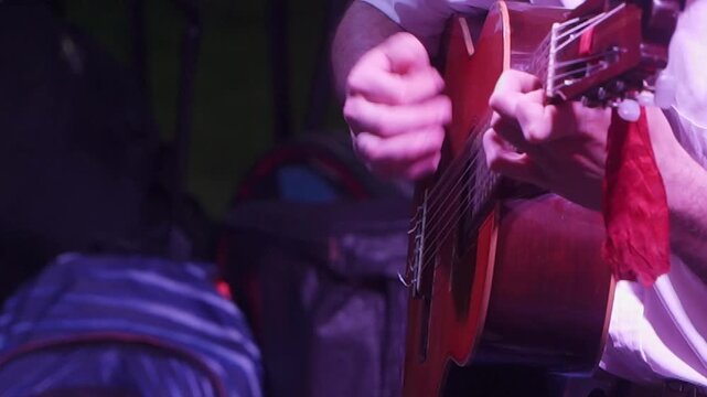 Close-up of a guitar player strumming a "chacarera" on a nylon-string guitar.