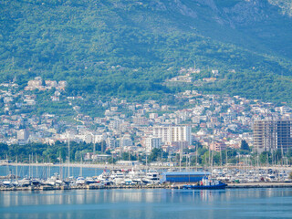 Scenic view of yacht club and marina in Bar, Montenegro, with boats, city buildings, and mountains in the background.