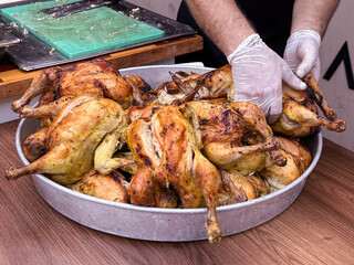 Cook slicing roasted chicken on a cutting board in a kitchen setting. Culinary preparation, food service, and gastronomy.