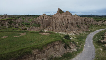 Badlands Peaks and Grass Patches Along Curving Dirt Trail in Rugged Terrain