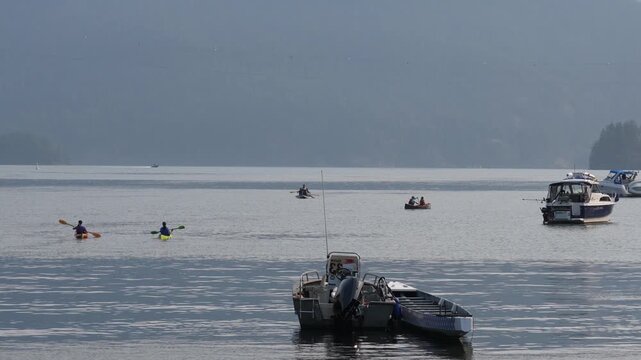 Kayakers and Boats on Tranquil Lake with Mountain Backdrop on Calm Summer Day
