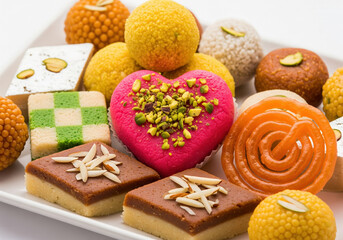 A vibrant close-up of a platter filled with various colorful and intricately decorated traditional Indian sweets