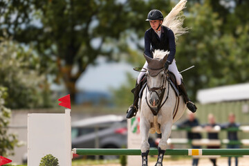 Close-up portraits of a show jumper jumping over an obstacle in a competition.