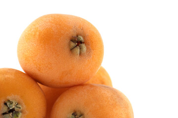 A close-up of a pile of fresh, ripe loquats, showcasing their orange color against white.