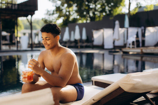 Young man relaxing poolside enjoying a refreshing drink