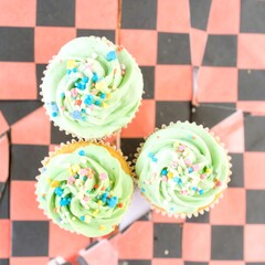 Three pastel cupcakes, colorful sprinkles