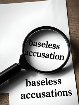 Magnifying glass and paper with the words baseless accusations. A false accusation is a claim or allegation of wrongdoing that is untrue and/or otherwise not supported by facts.