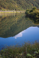 The mountain forest is reflected in the clear blue lake