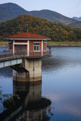 There is a red-roofed house on a blue lake in the mountains.