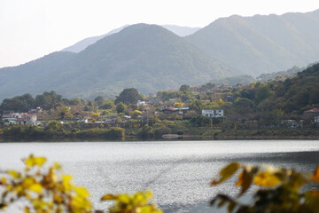 Behind the clear lake, mountains and rural villages are visible.