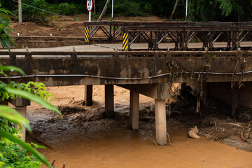 Floodwater flowing under damaged concrete bridge after heavy rain disaster