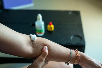 Medical care concept cotton swab pressed on injection wound on Asian woman’s arm in clinic