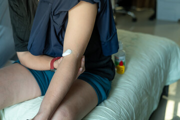 Asian woman’s arm with cotton swab on injection wound for wound care, vaccine