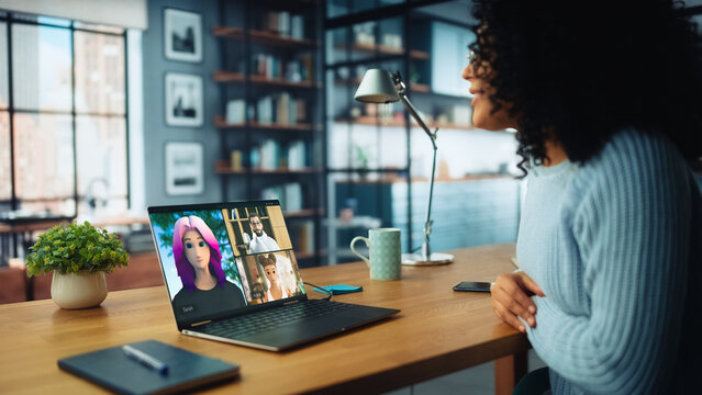 Woman in Home Office Participates in Video Call With  Colleagues and Friends using 3D animated Avatars. Laptop Displays Diverse Virtual Meeting. ModernCommunication via Social Media - Powered by Adobe