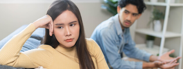 Naklejka premium Family problem concept. Tension in relationship between married couple, husband and wife staying sitting separate after quarrel in the living room.