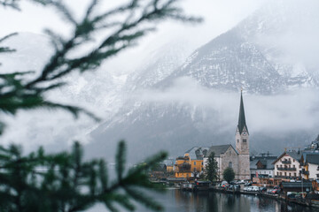 Misty winter view of Hallstatt village with church and traditional alpine houses by the lake