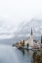 Close-up view of Hallstatt church and lakeside buildings under winter fog