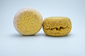 Two natural bath sponges in yellow and white color, placed side by side on a clean white background. Suitable for hygiene, skincare, bathroom essentials, eco friendly lifestyle, sustainability