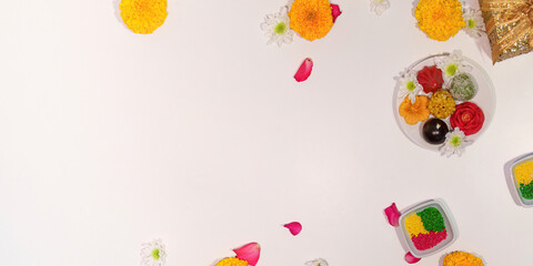 Diwali sweets and flowers scattered on a clean white surface