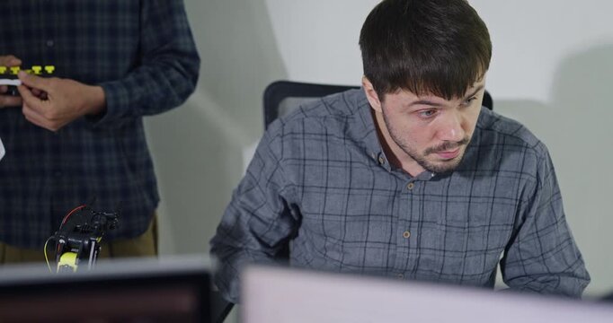 Closeup team adult male engineer collaborate on robotic hand project using AI code solutions machine learning at tech workspace. Artificial intelligence interface, collaboration prototype development.