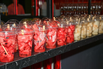 Cups filled with fresh watermelon and melon pieces served as vegan snacks on a party table, ready for guests as healthy summer refreshments.