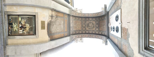 A monumental archway with a clock and classical columns, located in a cobblestone square in the...