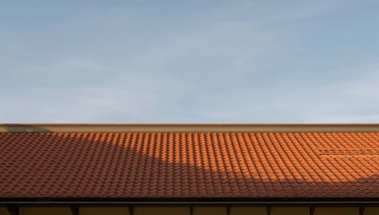 Fototapeta premium A terracotta tiled roof against a softly lit blue sky during a serene day, capturing a peaceful atmosphere
