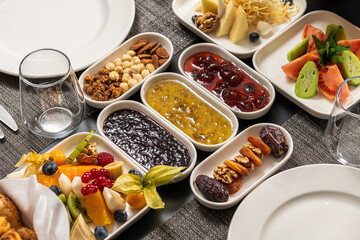 Assorted breakfast platter with jams, fruits, nuts, and cheese