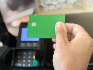 Contactless payment holding green credit card with touch settlement paying for shopping nfc technology transaction cashless technology and credit card payment. Paying with a contactless bank card.