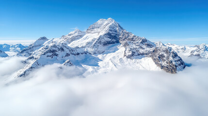 Obraz premium Majestic snowy mountain peaks rise above dense clouds clear blue sky, creating breathtaking view
